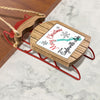 Wooden sled ornament with "Merry Christmas From Saylorville Lake" text and snowflakes.