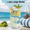 Glass of lemonade with limes and mint on a beach with a sailboat.