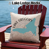Pillow with Lake Gregory map and compass design, sitting on a chair by the water.