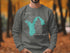 Gray sweatshirt with a teal map of Washington and compass graphic.