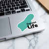 Turquoise map sticker with "Convict Life" text on a laptop keyboard.
