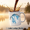 White mug with Lake Massabesic and compass design, coffee pouring in.