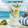 Glass with drink, lime, mint, and lake map design on beach background.