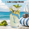 Glass of lemonade with lime and mint, beach background, sunglasses on pillow.