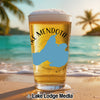 Beer glass with "Lake Mendota" and Wisconsin map on beach with palm trees.