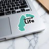Teal sticker with black text "grand Life" on a laptop keyboard.
