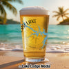 Beer glass with a compass and lake design on a beach background.