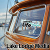 Gaston Life sticker on a wooden boat window, with "Lake Lodge Media" logo below.
