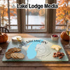 Textured glass cutting board featuring a blue map of Lake Michigan, compass rose, and snacks on a wooden table.