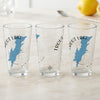 Three clear glasses with blue maps of Trout Lake, New York, and compass graphics.