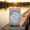 A white stainless steel stemless wine tumbler with a compass and Lake Granbury, Texas graphic, resting on a wooden dock.