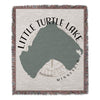 Woven blanket with a green Little Turtle Lake shape, compass, and text.