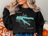 Black sweatshirt with turquoise Fellows Lake map and compass graphic.