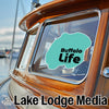 Teal Buffalo Life sticker on a wooden boat window, with Lake Lodge Media logo.