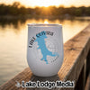 A white insulated tumbler featuring a blue outline of Lake Quivira, Kansas, sitting on a wooden dock at sunset.