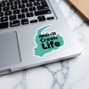 Teal sticker with black text "Merrill Creek Life" on a laptop.