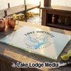 A glass cutting board featuring a Lake Hartwell map and compass design sits on a wooden dock.
