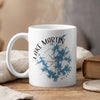 White mug with Lake Martin Alabama map and compass design, emitting steam.