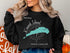 Black sweatshirt with a teal map of Kiawah Island, South Carolina and compass rose.