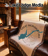 Woven blanket with Great Sacandaga Lake map design draped on leather sofa.