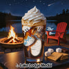 Glass of coffee with whipped cream next to s'mores ingredients by a campfire.