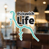 Pickwick Life text and abstract turquoise shape sticker on a dirty glass surface.
