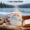 White mug with Flagstaff Lake map and compass on a rainy day with a book and scarf.