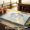 A glass cutting board featuring a blue map of Lake Allatoona with a compass rose design on a wooden table.