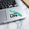 Green map outline sticker with "Waurika Life" text on a laptop.