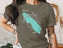 T-shirt featuring a turquoise silhouette of Onondaga Lake with compass rose and text.