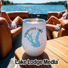 A white travel wine tumbler sits on a wooden boat table featuring a Calaveras Lake Texas design.