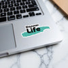 Sticker with "Donner Life" text on a laptop with a marble background.