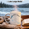 White mug with "Highland Lakes Texas" and compass graphic next to a book and scarf.