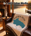 Walden Pond Massachusetts throw blanket on a leather couch with fireplace view.