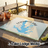 A glass cutting board featuring a blue map of Lewisville Lake, Texas, sits on a wooden bar overlooking a body of water.