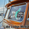 Turquoise Long Pond Life sticker on a wooden boat window, "Lake Lodge Media" text below.