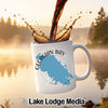 White mug with Georgian Bay map design and splashing coffee on a misty lake background.
