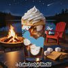 Drink with whipped cream on top near a campfire and lake at night.