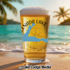 Glass of beer with "Enada Lake" and map design, on a beach at sunset.