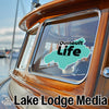 "Quinault Life" logo sticker on a wooden boat cabin window with "Lake Lodge Media" text below.