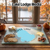 Glass cutting board featuring a map of Ossipee Lake, New Hampshire, on a wooden table with snacks.
