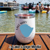 A white insulated wine tumbler featuring a map graphic rests on a wooden dock with people and boats in the background.