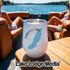 A white insulated wine tumbler with a Carlyle Lake Illinois graphic rests on a wooden boat table.