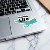 Sticker with "Harlan Life" text and a turquoise lake outline on a laptop keyboard.
