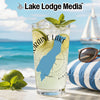Glass with "Moraine Lake" and blue lake outline, on beach with sailboat.