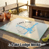 A glass cutting board featuring a blue Lake Lure, North Carolina map graphic and compass design.