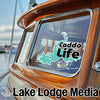 Turquoise Caddo Lake outline with text "Caddo Life" on boat window, "Lake Lodge Media" text below.