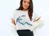 White t-shirt with "Alder Lake" text, a blue lake map and compass rose
