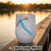 A white stainless steel tumbler featuring an Otisco Lake map and compass design sits on a wooden dock.