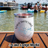 A white insulated tumbler with a Lewis Smith Lake compass design sits on a wooden boat deck.
